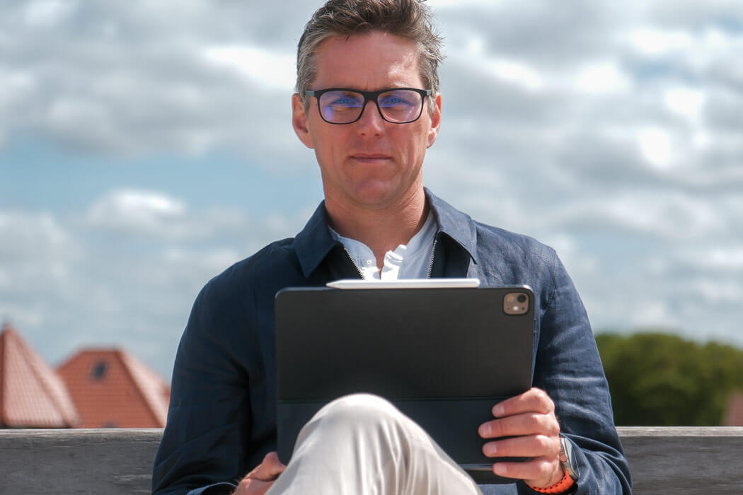 Geschäftsführer Jens Buss sitzt mit einem iPad in der Hand auf einer Bank